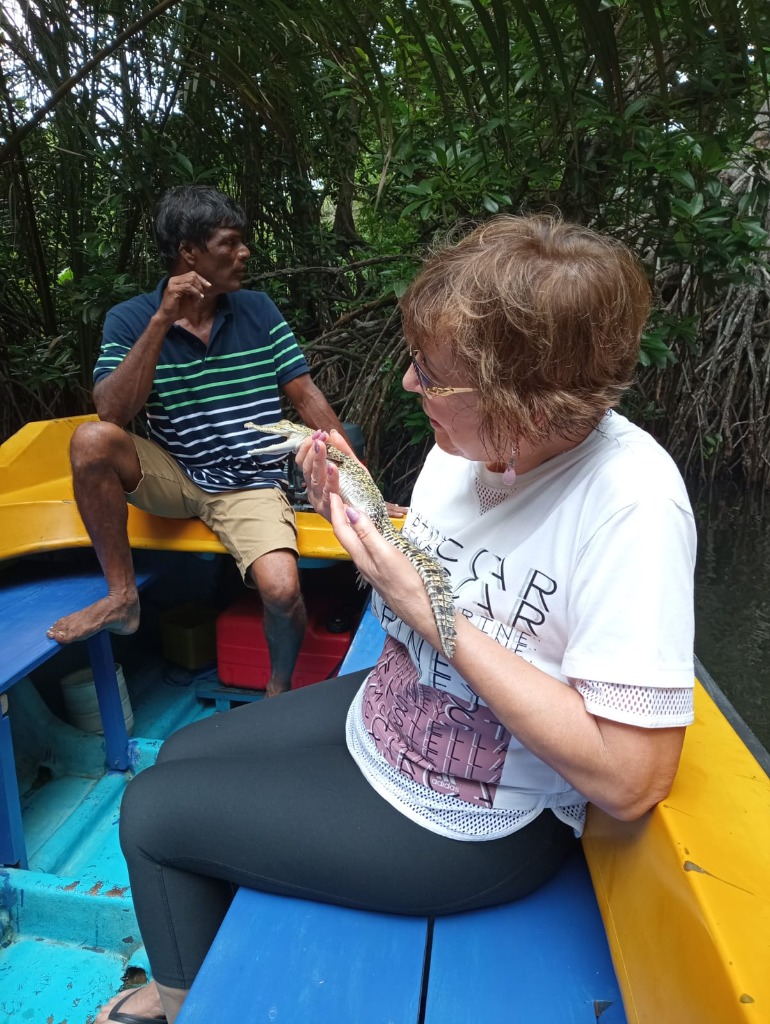Guest holding baby crocodile on Madu River boat safari